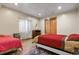 Cozy bedroom with wood laminate flooring, natural light, and a red quilt on a white metal bedframe at 634 County Road 37, Brighton, CO 80603