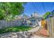 Backyard area featuring a wooden fence, grass, deck, table, chairs, and landscaping at 1208 S Pennsylvania St, Denver, CO 80210