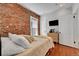 Bedroom features exposed brick, hardwood floors, and lots of natural light through the window at 1208 S Pennsylvania St, Denver, CO 80210