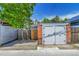 A detached two car garage with white doors and brick pillars, next to a wooden fence at 1208 S Pennsylvania St, Denver, CO 80210