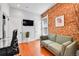 Living room showcasing exposed brick accent wall, hardwood flooring, and a comfortable loveseat at 1208 S Pennsylvania St, Denver, CO 80210