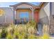 Cozy front porch with seating, a bright orange door, and charming stone accents on the exterior at 22646 E Glidden Dr, Aurora, CO 80016