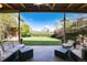 Covered patio area with comfortable seating overlooks the lush backyard and mature trees at 7000 Highland Dr, Lakewood, CO 80214