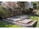 A charming garden featuring stone-lined planting beds and a neatly stacked woodpile surrounded by trees at 7000 Highland Dr, Lakewood, CO 80214