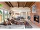 Open concept living room with beamed ceiling, exposed brick fireplace, large windows and comfortable seating arrangements at 7000 Highland Dr, Lakewood, CO 80214