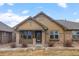 Single-Gathering home featuring stone accents, a covered front porch, and manicured landscaping at 8555 W Quarles Pl, Littleton, CO 80128