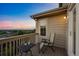 A cozy outdoor balcony provides open views of the horizon at dusk with a table and comfortable chair at 10837 Fox Sedge Way, Highlands Ranch, CO 80126