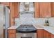 A kitchen with a stainless steel gas range and oven, as well as wooden cabinets and a tile backsplash at 1080 E 13Th Ave # 301, Denver, CO 80218