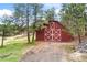 Spacious barn with large doors and white trim details, surrounded by lush greenery and mature trees at 1730 Ward Cir, Franktown, CO 80116