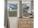 Bedroom detail showing a wooden dresser, two windows with neutral curtains, and greenery at 1730 Ward Cir, Franktown, CO 80116