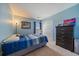 Cozy bedroom featuring a large window, closet, dark dresser, and a bed with blue striped bedding at 9800 Mayfair St # E, Englewood, CO 80112