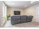 Cozy basement with a comfortable gray reclining couch, a television, and a neutral carpet at 2868 Kingston St, Denver, CO 80238