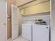 A laundry room with a modern white washer and dryer, shelving above, and a tiled floor at 7500 E Dartmouth Ave # 22, Denver, CO 80231
