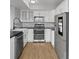 Modern kitchen featuring stainless steel appliances, sleek countertops, white cabinetry, and wood flooring at 13633 E Yale Ave # B, Aurora, CO 80015