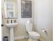 Clean powder room featuring a pedestal sink, toilet, and framed wall art at 12628 Bayshore St, Firestone, CO 80504