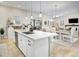 Open kitchen with white cabinets, island seating, and a view into the dining area at 12628 Bayshore St, Firestone, CO 80504