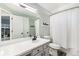 This bathroom features a shower with a white curtain, a toilet, a sink and gray-painted walls at 6184 Clayton St, Frederick, CO 80530