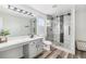 This bathroom features a glass shower stall, wood floors, white walls, a vanity, and a toilet at 6184 Clayton St, Frederick, CO 80530