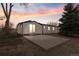 Home's backyard features a concrete patio, sunset skies, and mature trees, ideal for outdoor living at 11640 W 13Th Ave, Lakewood, CO 80401