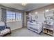 Cozy Bedroom with crib, accent wall, and bright window showcasing exterior views at 1200 Sugarloaf Ln, Erie, CO 80516