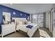 Bright bedroom with a blue accent wall, dresser, many pillows, and natural light from windows at 1200 Sugarloaf Ln, Erie, CO 80516