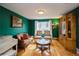 Vibrant living room with green walls, hardwood floors, and an eclectic mix of furniture creating a charming space at 2829 S Fig St, Lakewood, CO 80228