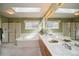 Spacious bathroom featuring a skylight, a large mirror, double sinks, a soaking tub, and a separate glass shower at 2829 S Fig St, Lakewood, CO 80228