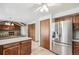 Open kitchen with stainless steel refrigerator, wooden cabinets, tile floors, and a view into the living room at 9431 W Jewell Pl, Lakewood, CO 80227