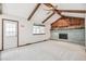 Spacious living room featuring a brick fireplace, beamed ceilings, and natural light from large windows at 9431 W Jewell Pl, Lakewood, CO 80227