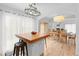 Stylish kitchen island with seating adjacent to the dining and living rooms with hardwood floors throughout at 3695 Quail St, Wheat Ridge, CO 80033