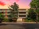 Brick apartment building exterior with lush trees and manicured bushes at dusk at 2500 S York St # 204, Denver, CO 80210