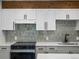 Updated kitchen with white cabinets, modern backsplash, and stainless steel appliances at 2500 S York St # 204, Denver, CO 80210