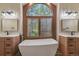 Bright bathroom featuring dual sinks, freestanding tub, a large arched window, and wood-look flooring at 19165 Golden Arrow Cir, Monument, CO 80132