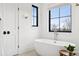 Bright bathroom featuring a soaking tub next to a window and black door at 815 E Westglow Ln, Greenwood Village, CO 80121