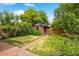 Lush backyard featuring a brick patio, vibrant flowers, and a detached brick garage at 346 N Corona St, Denver, CO 80218