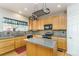 Well-lit kitchen boasts light wood cabinetry, black appliances, a mosaic backsplash, and an island with granite countertops at 2225 Clayton Cir, Superior, CO 80027