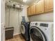 Efficient laundry room with shelving, cabinets, and modern washer and dryer units on tile flooring at 2225 Clayton Cir, Superior, CO 80027