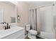 Bathroom featuring white vanity with a dark faucet, toilet, and shower-tub combination with tan shower curtain at 10150 E Virginia Ave # 104, Denver, CO 80247