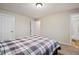 Bedroom with a bed with plaid pattern, two white doors, carpet, and an adjoining bathroom at 10150 E Virginia Ave # 104, Denver, CO 80247