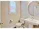 Powder room featuring pedestal sink, rounded mirror, and window with shutters at 5080 Uinta St, Denver, CO 80238