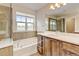 Elegant bathroom featuring a large soaking tub and wood cabinets for storage at 5080 Uinta St, Denver, CO 80238