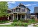 Two-story home features a covered front porch, gray siding, brown shutters, and a landscaped front yard at 5080 Uinta St, Denver, CO 80238