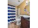 Well-lit bathroom featuring a vessel sink, round mirror, and blue and white striped shower curtain at 646 S Joplin St, Aurora, CO 80017