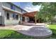 Backyard with a covered patio, hot tub, and steps leading up to the house, all surrounded by green grass at 8720 E 163Rd Pl, Brighton, CO 80602
