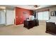 Home office with a red accent wall, dark wood desk, neutral carpet, and a ceiling fan at 8720 E 163Rd Pl, Brighton, CO 80602