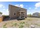 The home's backyard, featuring a wooden fence, small covered patio, and grass at 603 Jewel St, Brighton, CO 80603