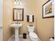 A bathroom with a pedestal sink, decorative mirror, and a toilet with decorations on the tank at 4965 Bierstadt Loop, Broomfield, CO 80023