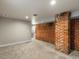 Unfinished basement features brick accent wall, gray carpet, and a nook with potential for additional amenities at 4495 Utica St, Denver, CO 80212