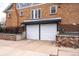 Brick home exterior featuring a large garage with white doors and black trim at 4495 Utica St, Denver, CO 80212