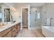 Modern bathroom featuring double vanity, walk-in shower, soaking tub and wood look tile floor at 119 Leafy Aster Ln, Castle Rock, CO 80104